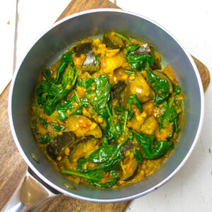 chopped aubergine mixed with spinach leaves and tomato and ginger sauce in a pan