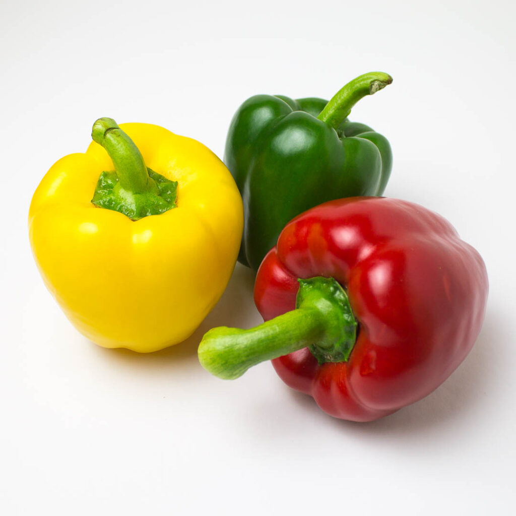 yellow, green and red bell peppers on a white background