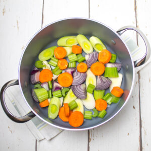chopped vegetables in a deep pan on a white wooden table