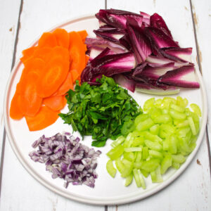 red chicory leaves, chopped red onion, parsley, celery and thinly sliced carrots arranged on a white plate