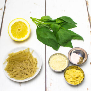 rice noodles, basil lemon , nutritional yeast, ground almonds and salt and pepper arranged on a white wooden table