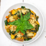 tomato based vegetable soup in a bowl topped with some basil leaves