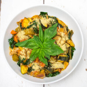 tomato based vegetable soup in a bowl topped with some basil leaves