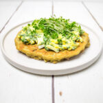 gluten free pancake topped with boiled eggs, chives and cress on a white plate