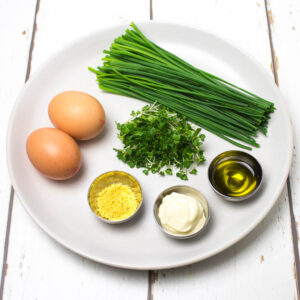 eggs, chives, cress and savoury pancake toppings on a white plate