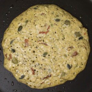 half cooked pancake in a frying pan