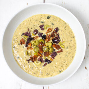 wet pancake mixture topped with chopped olives and sundried tomatoes in a white bowl