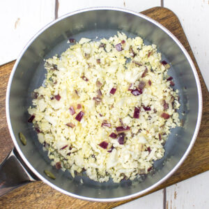a pan with cauliflower rice and red onion