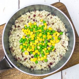 a pan with cauliflower rice, pea, corn and red onion