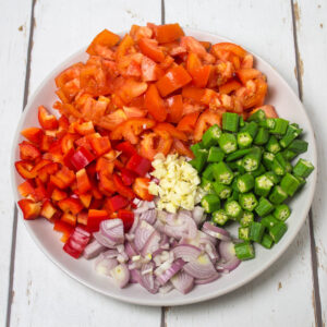 chopped tomatoes, red pepper, okra and finely chopped onion and garlic arranged on a plate