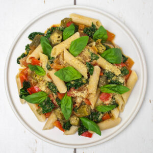 brown rice penne with tomato and vegetable sauce with toppings and basil leaves