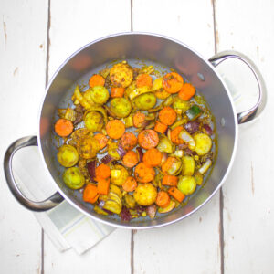 chopped vegetables mixed with turmeric and olive oil in a deep saucepan