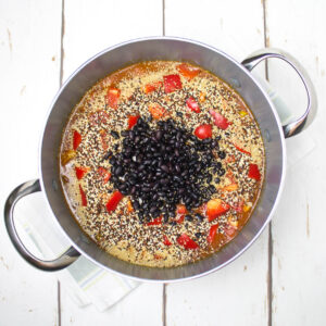 black beans and vegetables together with tomato sauce, quinoa and amaranth in a deep saucepan